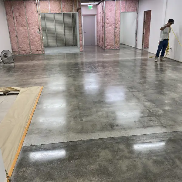 Worker crossing a freshly polished concrete floor in a partly built room