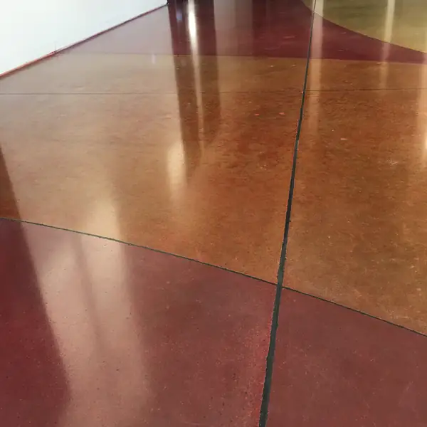 Orange and red stained polished concrete with a sweeping saw-cut curve