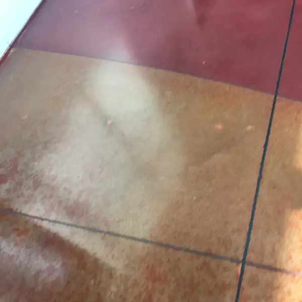 Deep red and orange stained polished concrete with a saw-cut joint