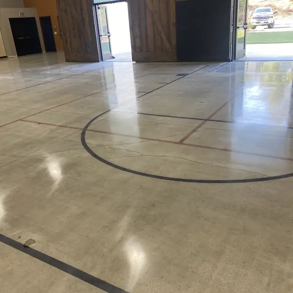 Polished concrete gym floor with a saw-cut circle and red court lines