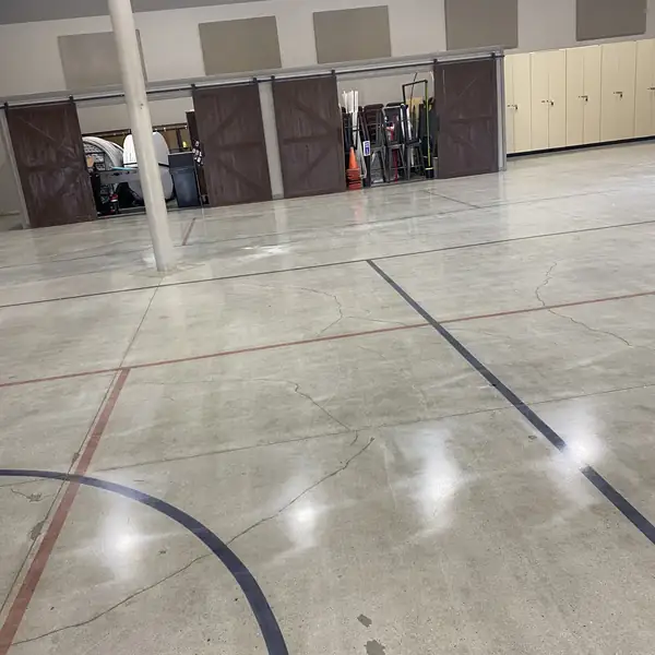 Polished concrete floor with saw-cut court markings in a multi-purpose hall