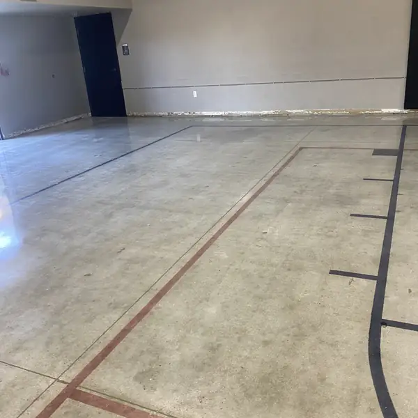 Saw-cut red and black court markings across a polished concrete floor