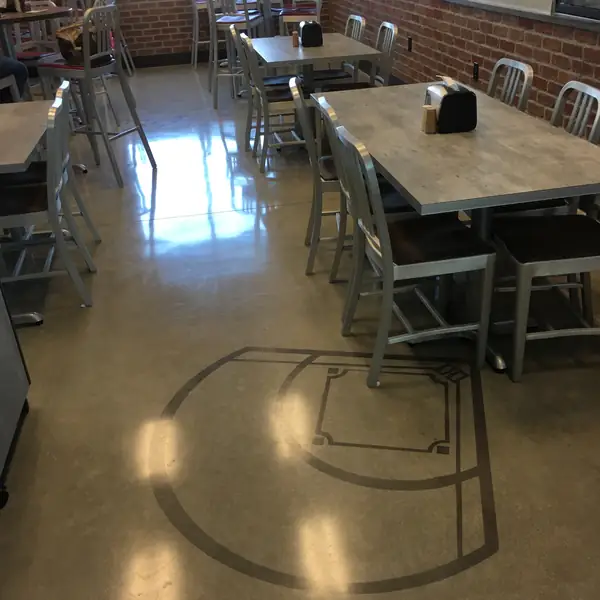 Polished concrete cafeteria floor with saw-cut graphics beneath the tables