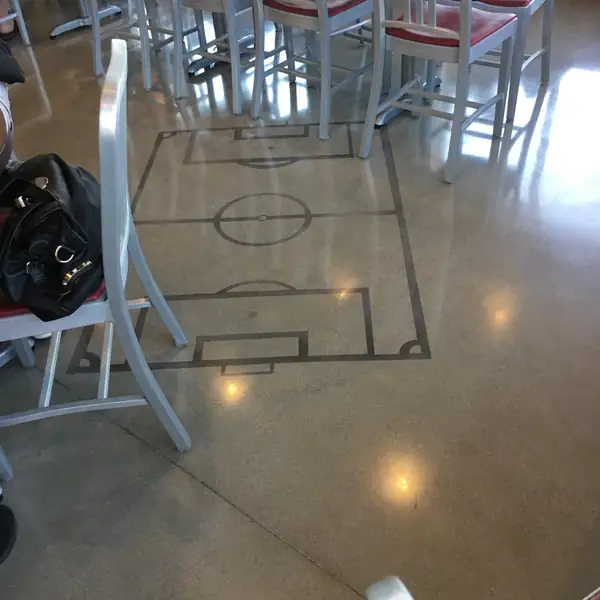Saw-cut pitch diagram in a polished concrete floor under cafe seating