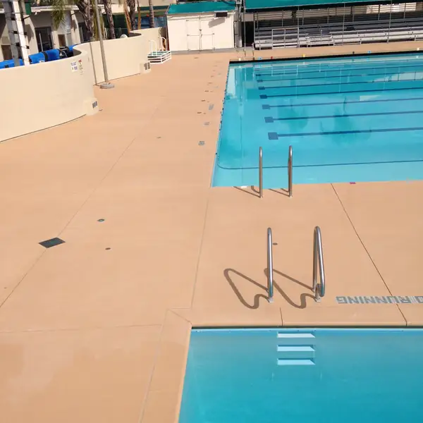Tan pool deck around a competition lap pool with lane markings in the water
