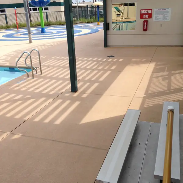 Splash pad and diving board area on a tan textured commercial pool deck