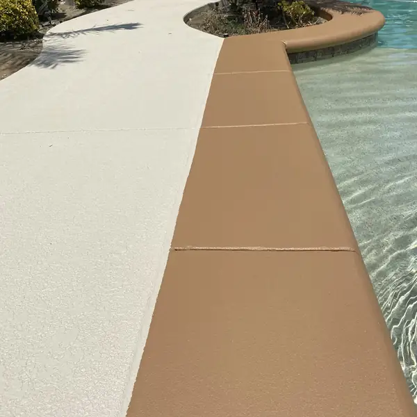 Tan coping band running between a cream deck and the pool water