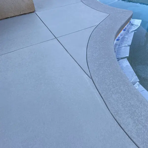 Blue-gray textured deck curving around the edge of a pool