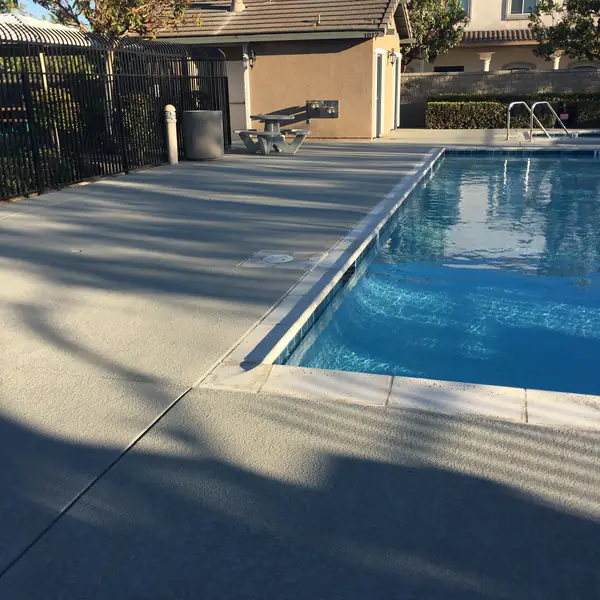 Pool with a gray textured deck and long evening shadows