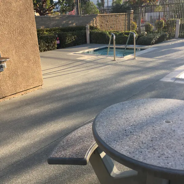 Community spa and pool deck in speckled gray with a shade wall