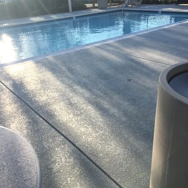 Sunlight raking across a freshly coated gray pool deck