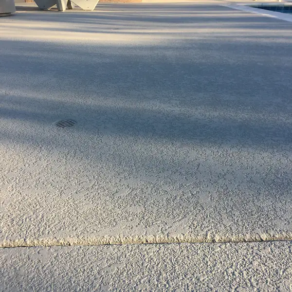 Gray pool deck with a drain set flush into the textured surface