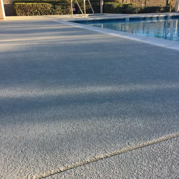 Gray textured deck running alongside a commercial lap pool