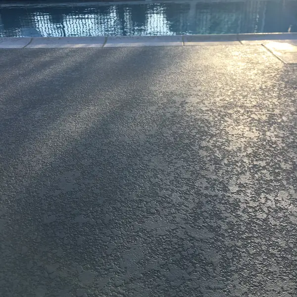 Gray pool deck with sunlight and shadow across the textured surface
