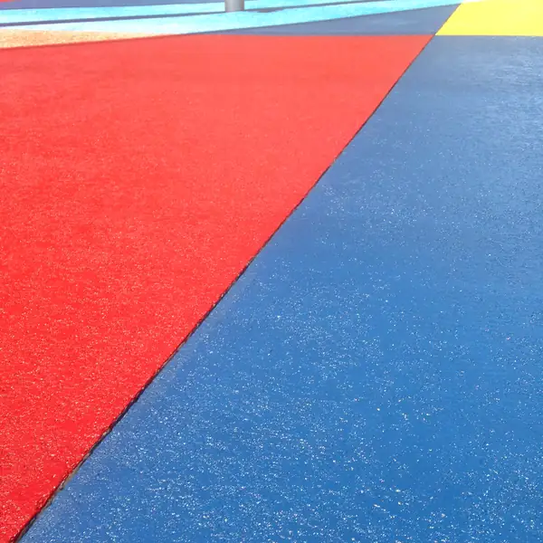 Red, blue and yellow coated panels meeting on a splash pad surface