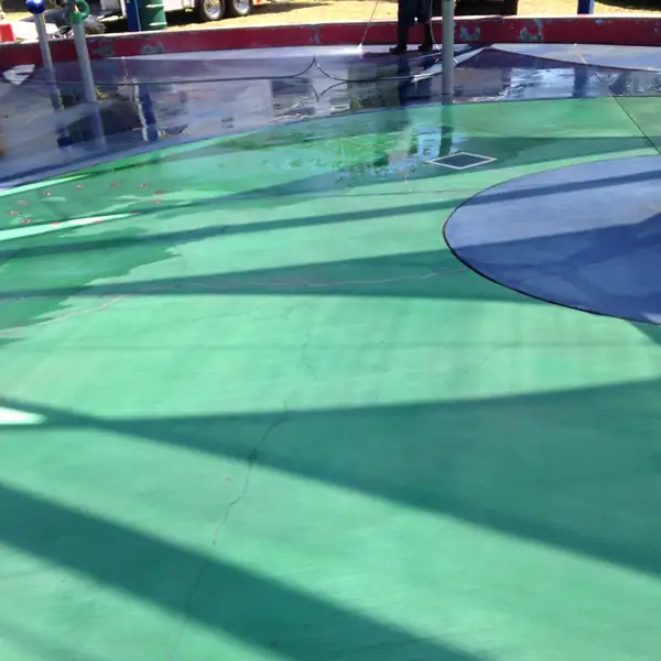 Green, blue and red splash pad coating under a play structure