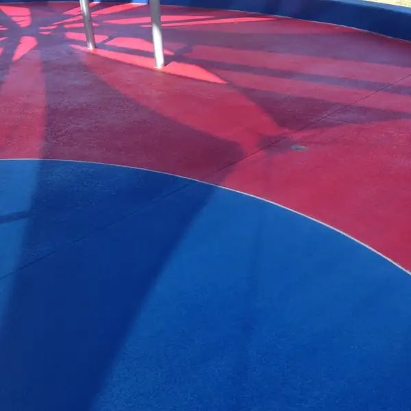 Red and blue curved splash pad coating around stainless play posts
