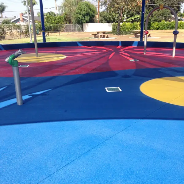 Park splash pad in red, blue and yellow with water play equipment