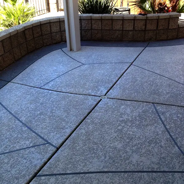 Blue-gray textured patio deck with a brick planter wall behind