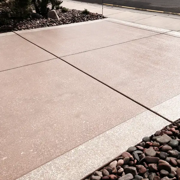 Tan textured deck edged with river rock landscaping