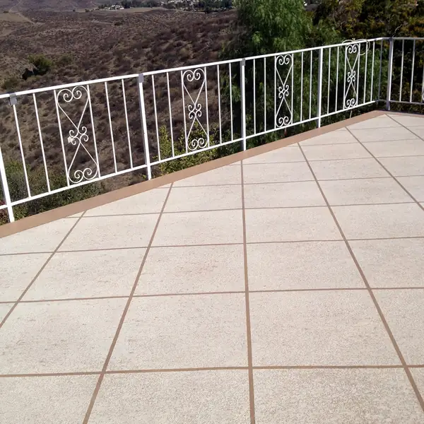 Tan textured patio deck behind a white railing with a valley view