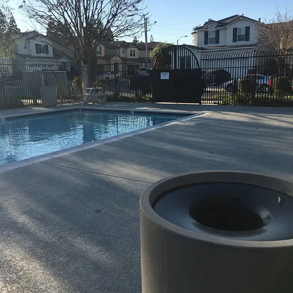 Apartment complex pool with a gray textured deck and metal fencing