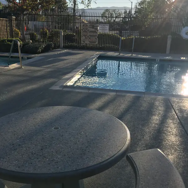 Gray textured deck and blue-gray border band running to a pool in low afternoon sun