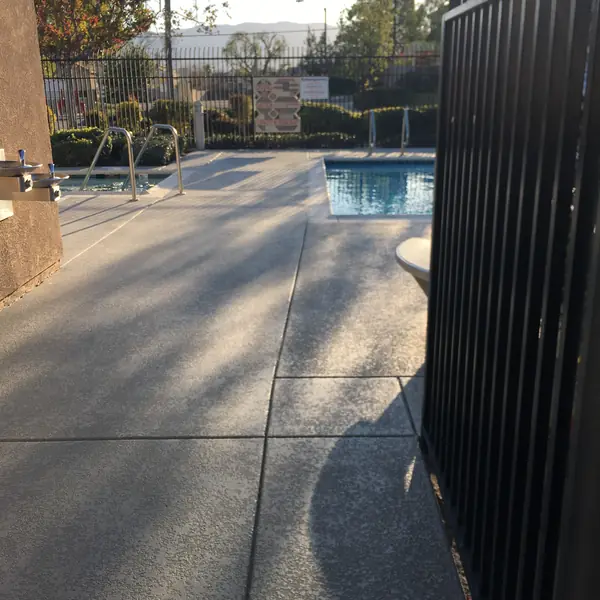 Blue-gray trim band along a gray textured deck beside a spa and pool