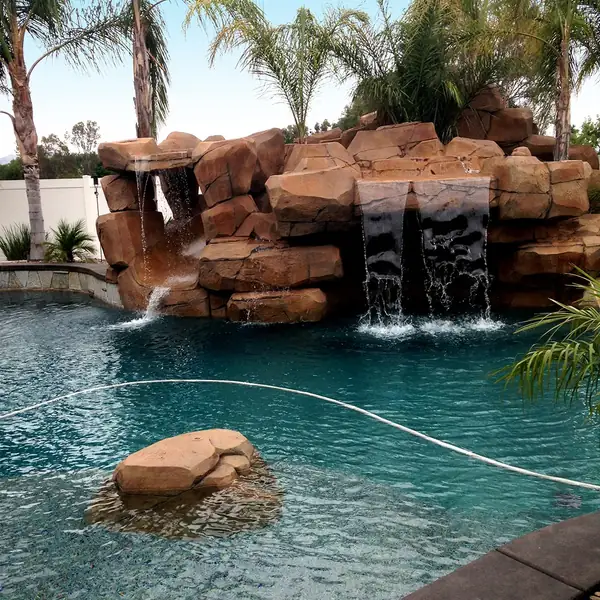 Rock waterfall feature and stained deck around a curved pool