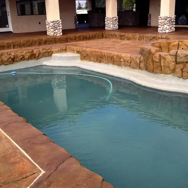 Stained pool deck and rock coping around a freeform pool