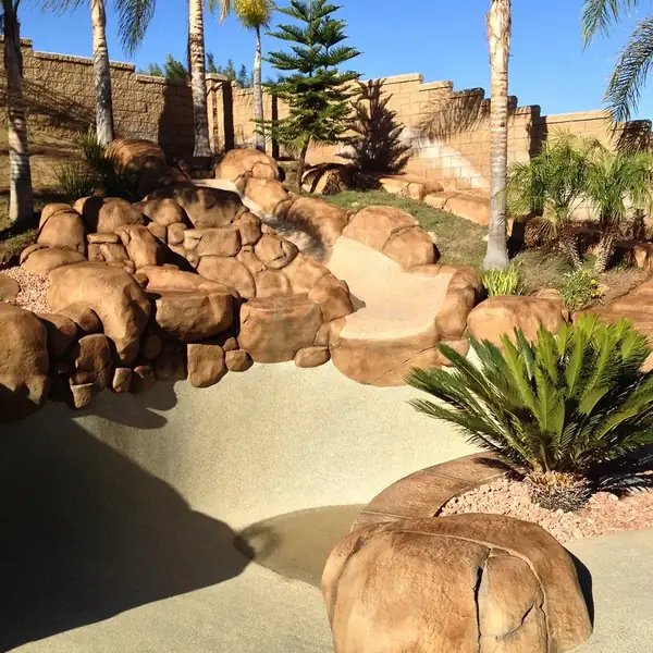 Restained boulder retaining wall with palms and desert planting
