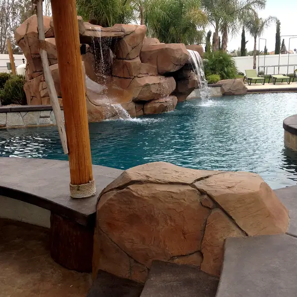 Rock waterfall beside a palapa post at the edge of a pool
