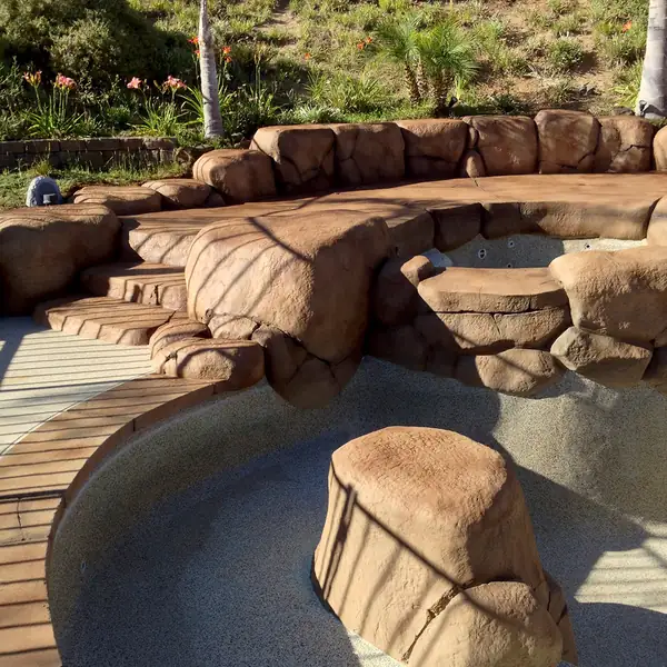 Curved stained deck meeting restained rock at a pool edge